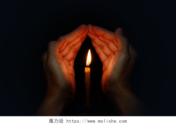 双手遮挡燃烧的蜡烛蜡烛点亮在手，祷告概念